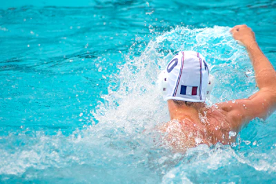 A focused coach guiding a team through a rigorous water polo training session.