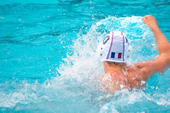 Youth water polo players practicing teamwork during an intense training session at a sunny outdoor pool.