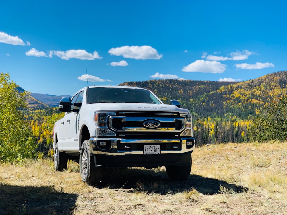 a white truck parked on top of a dry grass field