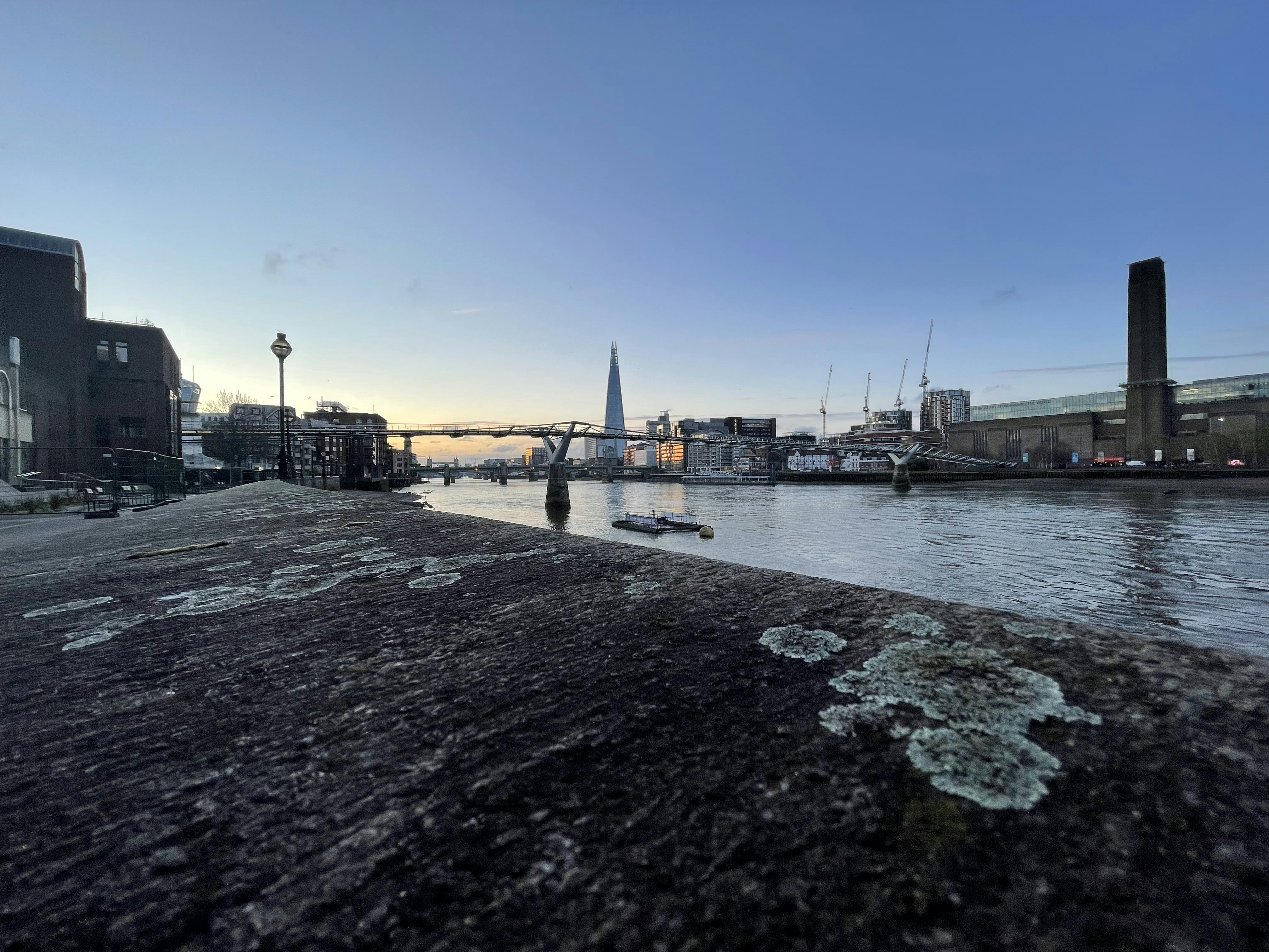 London early morning with misty Thames river, Tower Bridge illuminated, and city lights fading into dawn