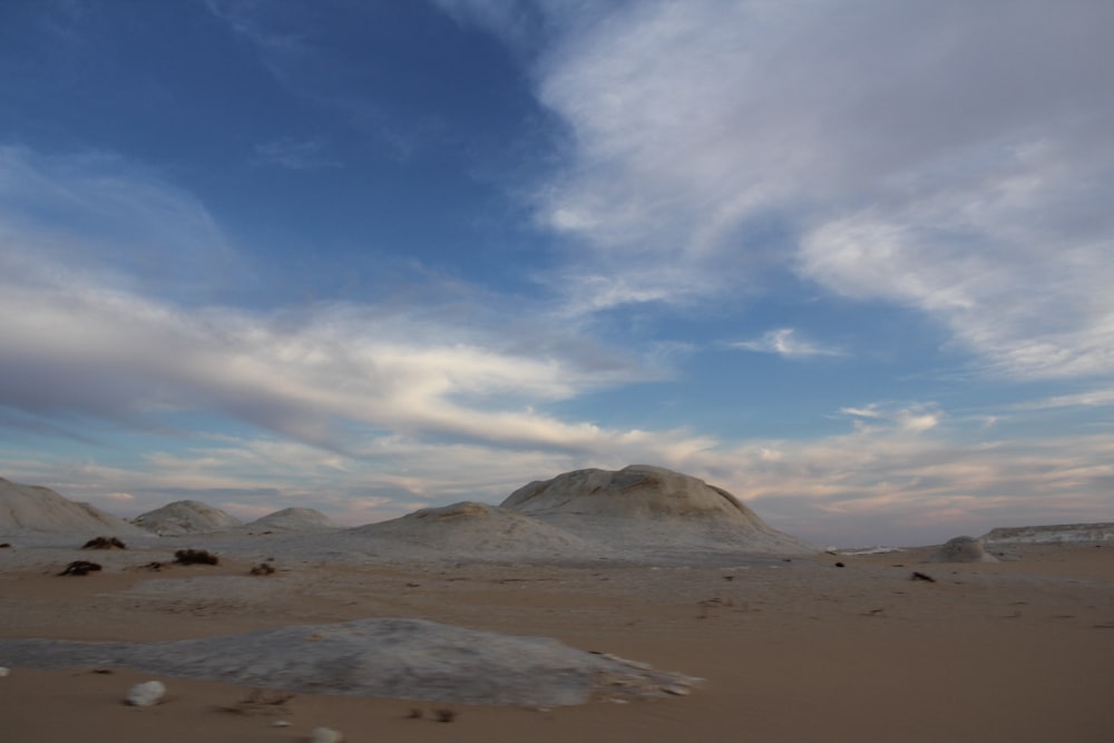 a desert landscape with sand and rocks under a cloudy sky