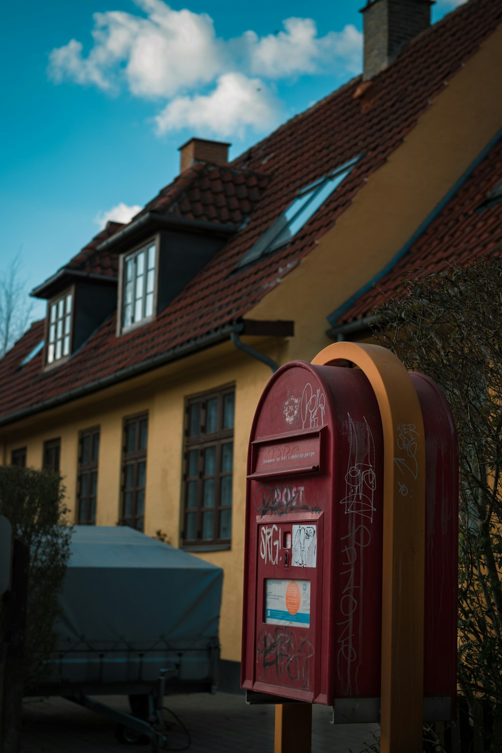 a red mailbox sitting in front of a yellow house