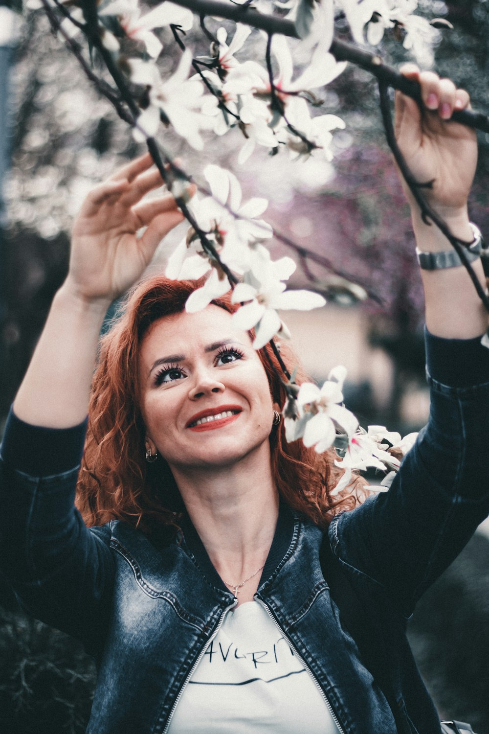 a woman holding a branch with white flowers