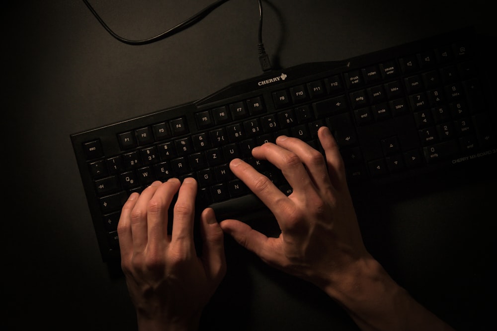 a person is typing on a black keyboard