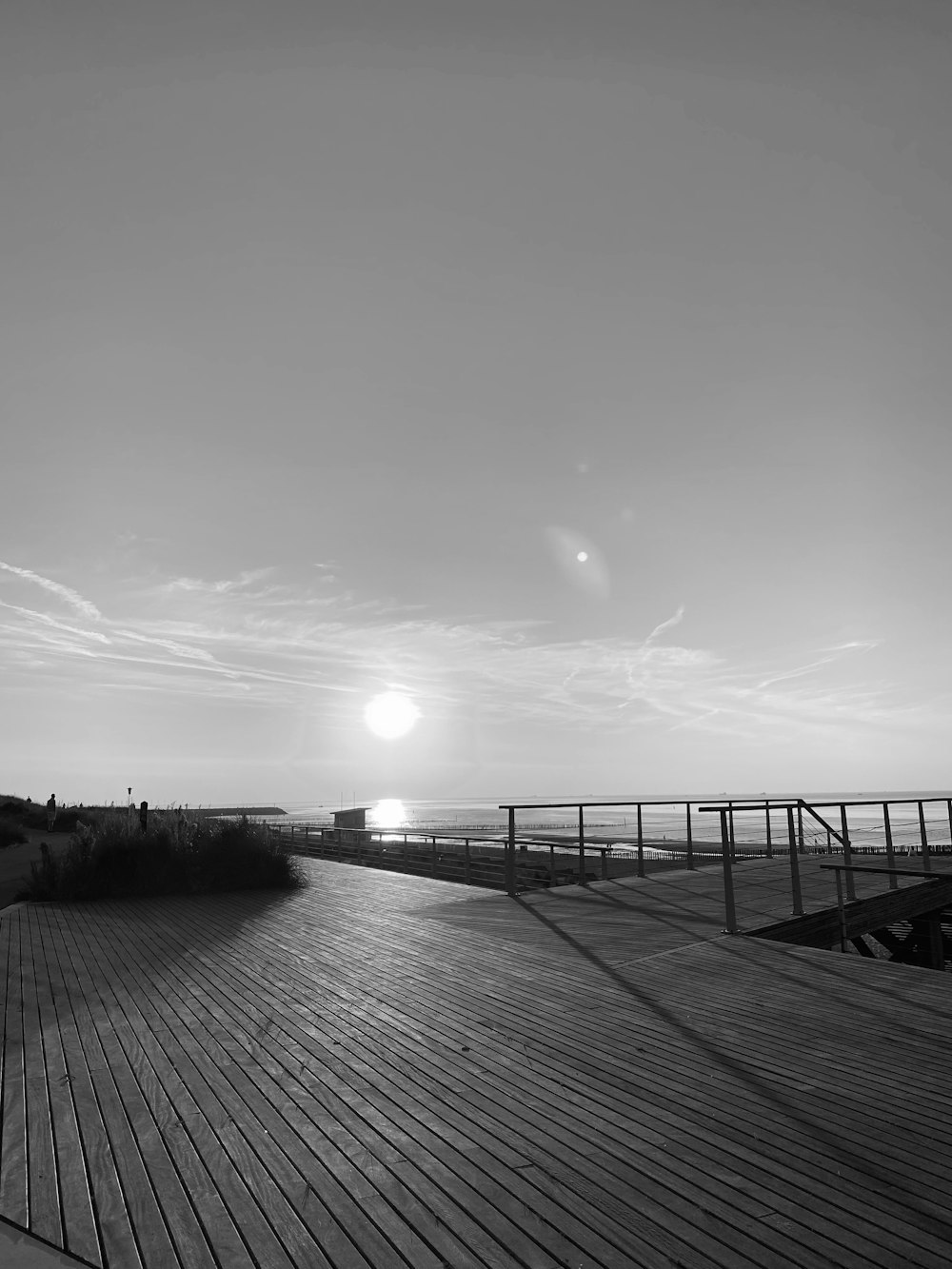 a black and white photo of a boardwalk at the beach