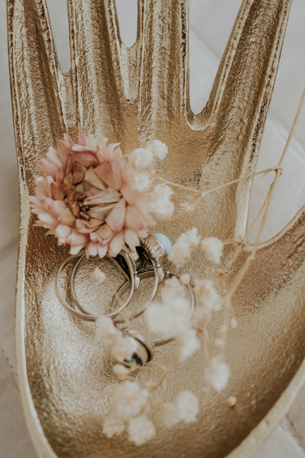 a pair of wedding rings sitting on top of a gold hand