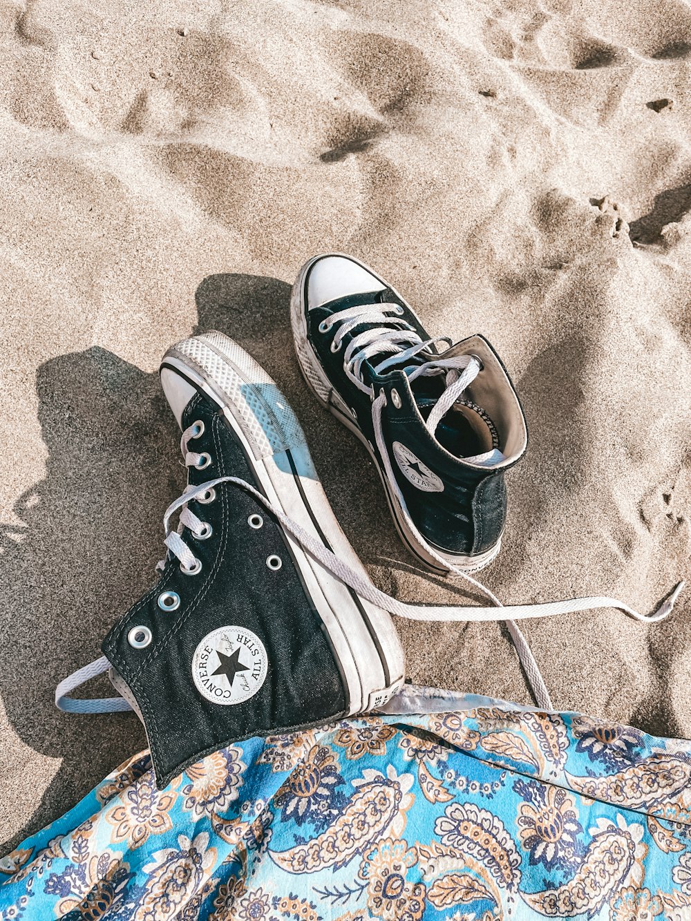 a pair of black and white converse shoes on a blanket