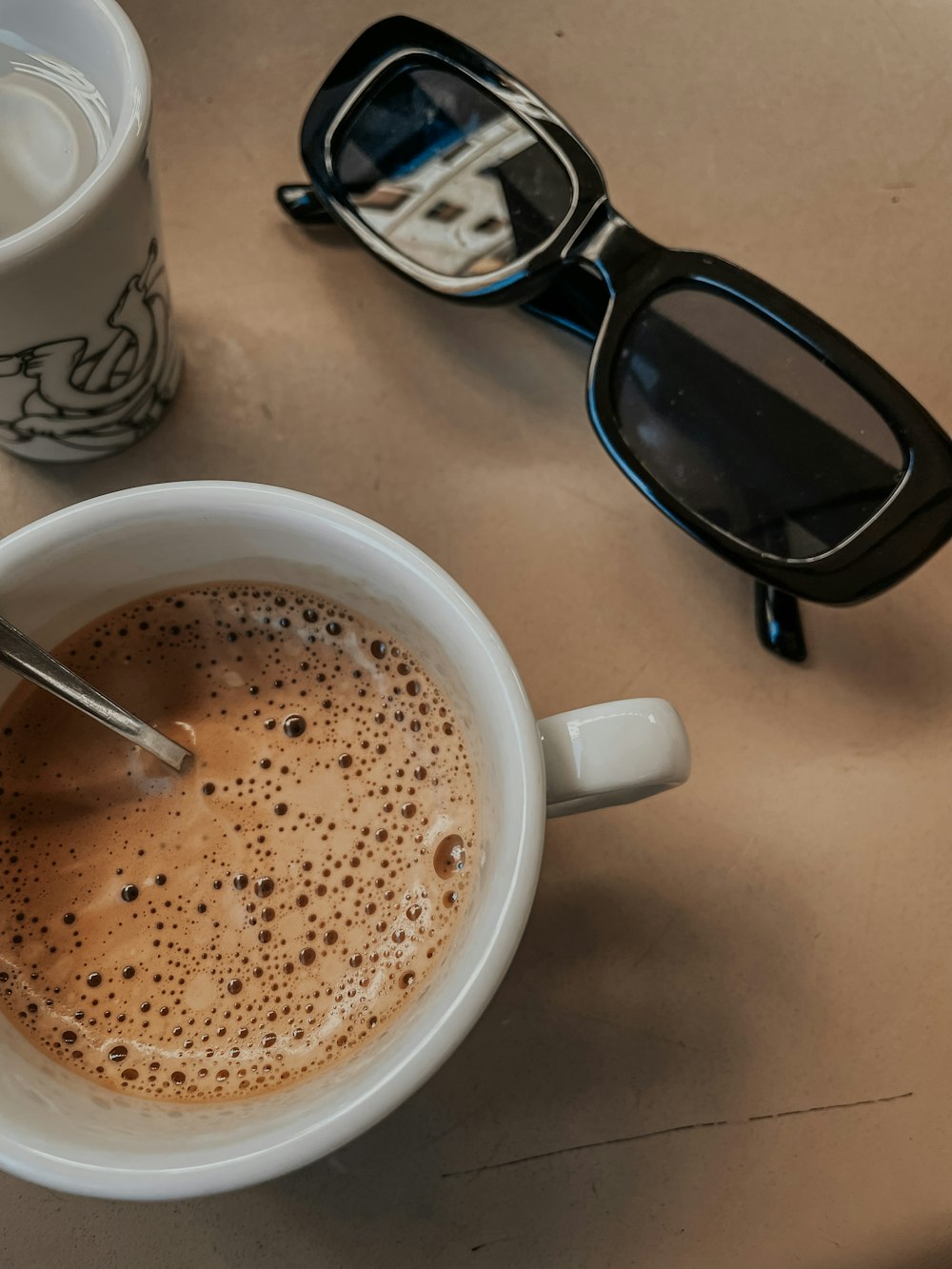 a cup of coffee next to a pair of glasses
