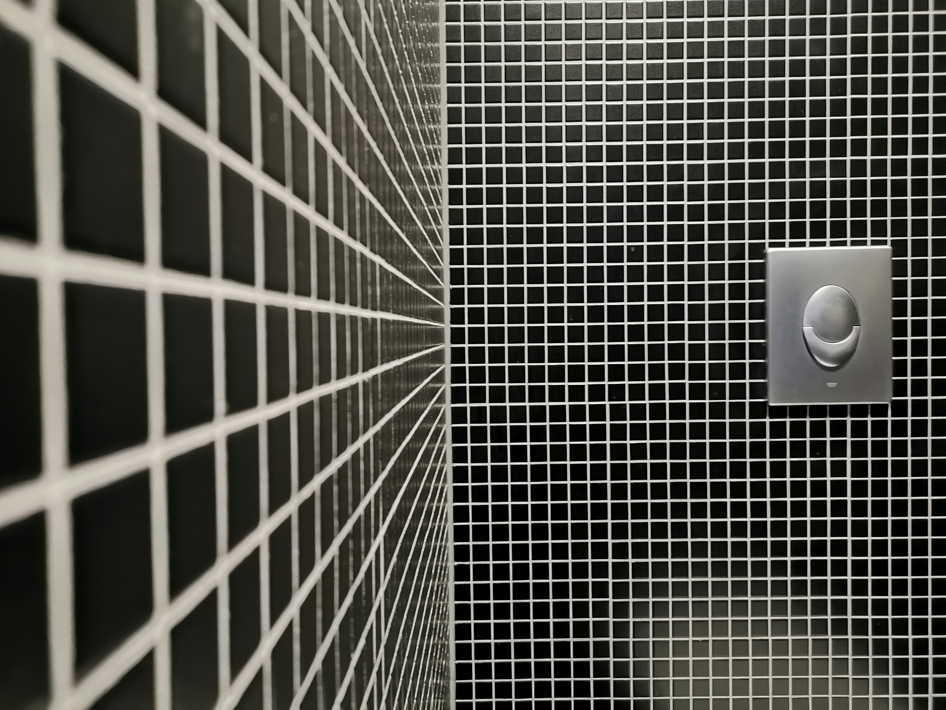 a black and white tiled bathroom with a toilet paper dispenser