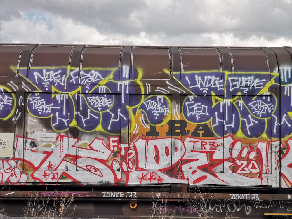 a train covered in lots of graffiti sitting on top of a train track