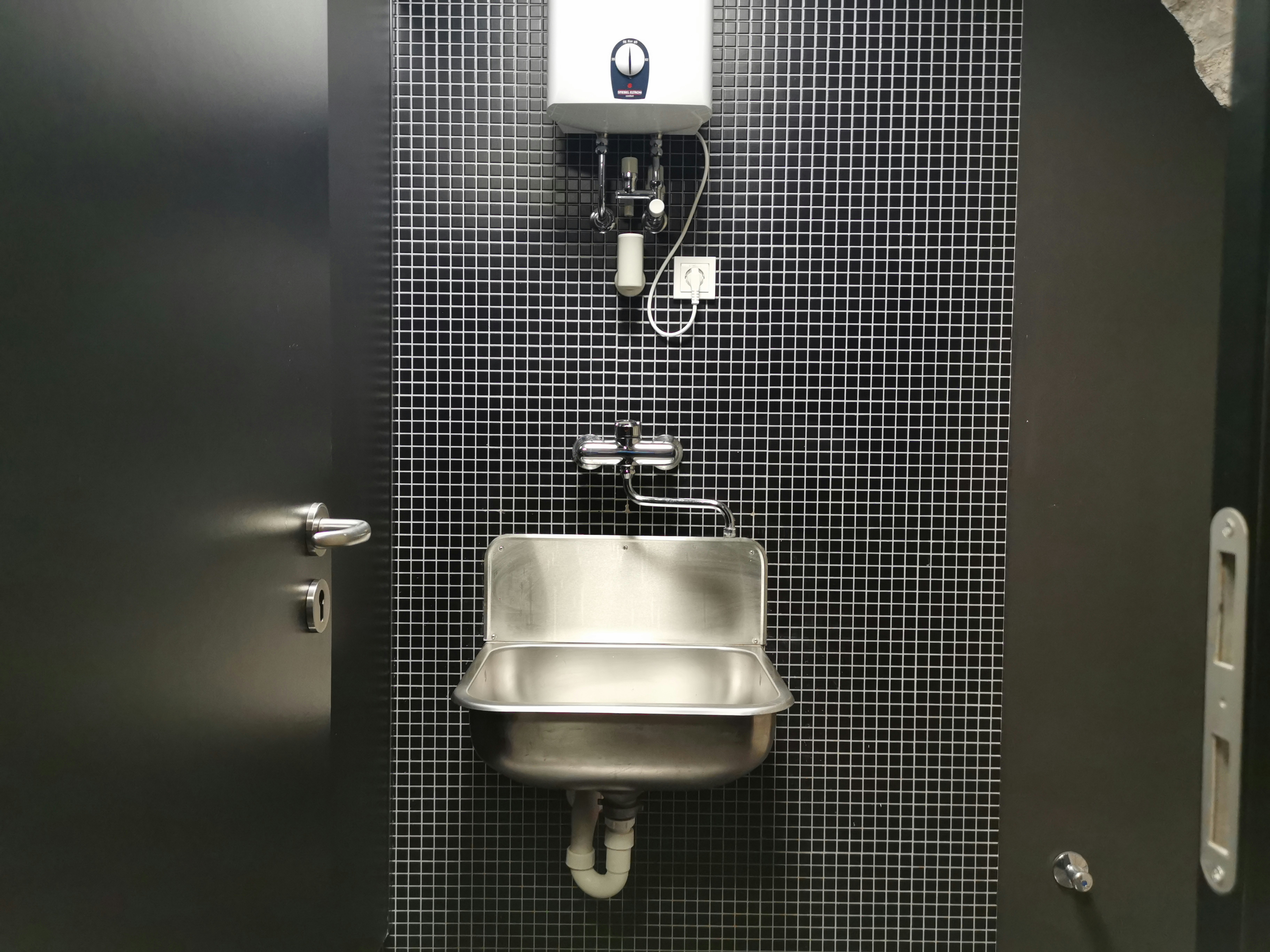 a bathroom stall with a sink and soap dispenser