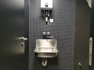 a bathroom stall with a sink and soap dispenser