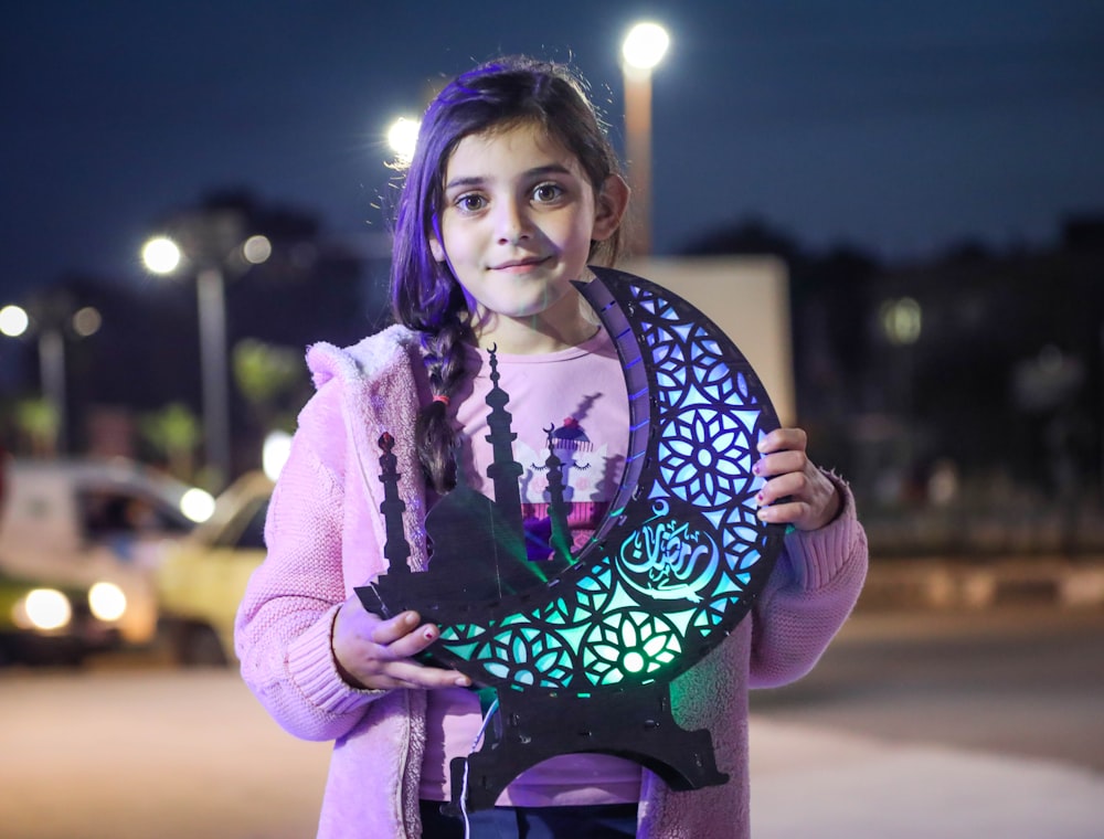 a young girl holding a cutout of a tree of life