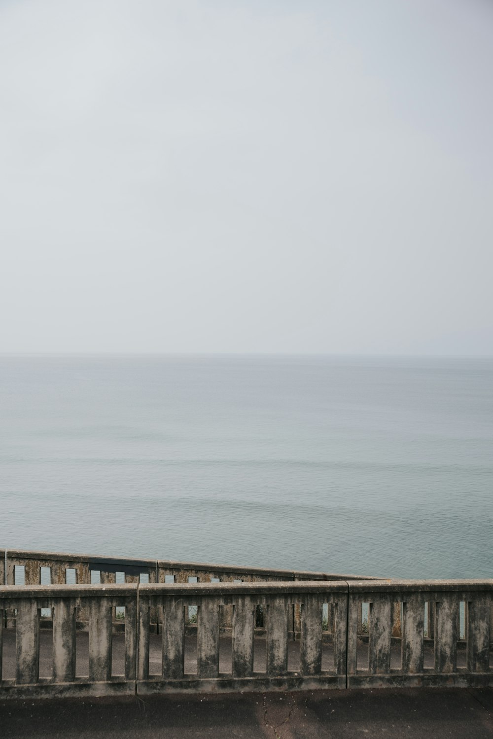 a person standing on a bridge over looking the ocean