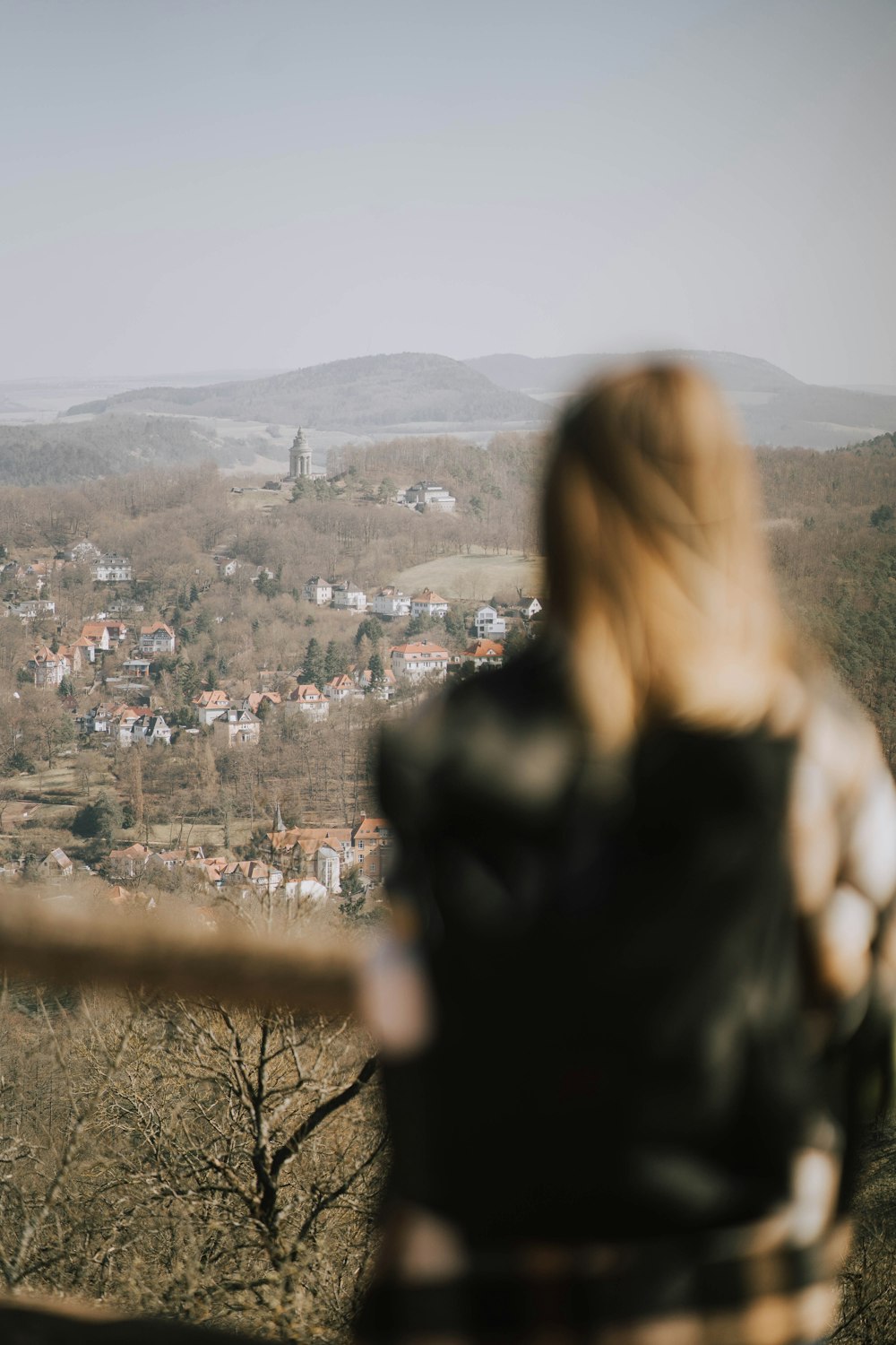 a woman standing on top of a hill overlooking a town