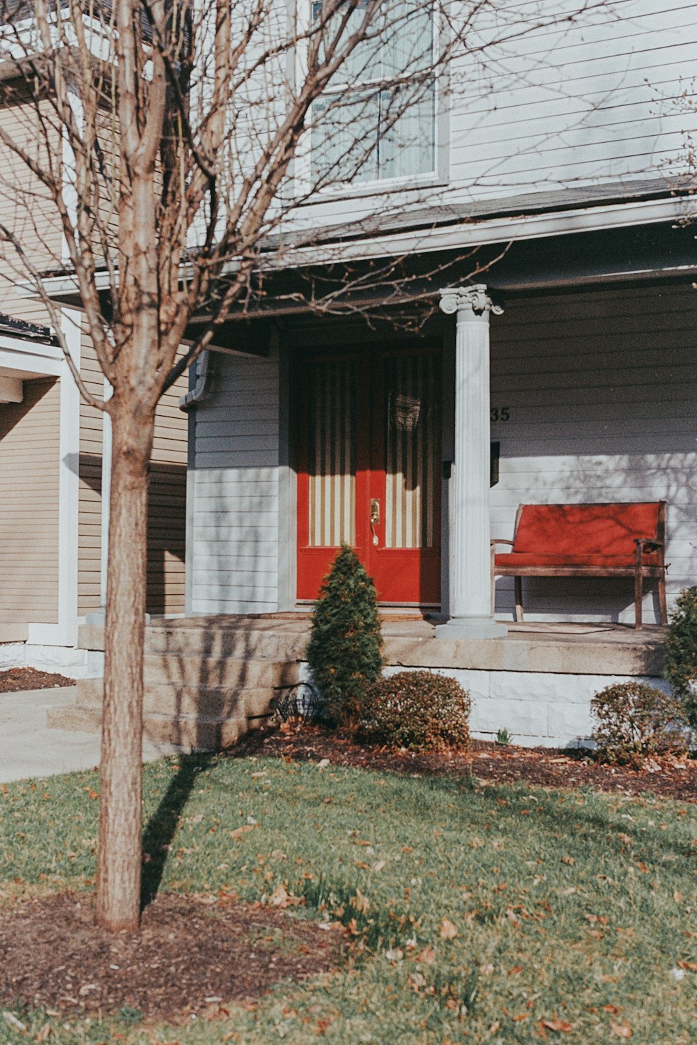 a house with a red door and a tree in front of it