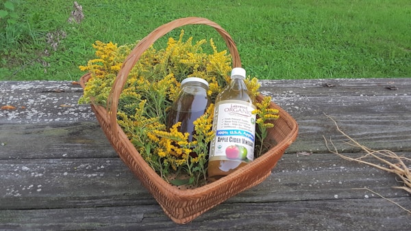 A basket filled with bottles of liquid and flowers