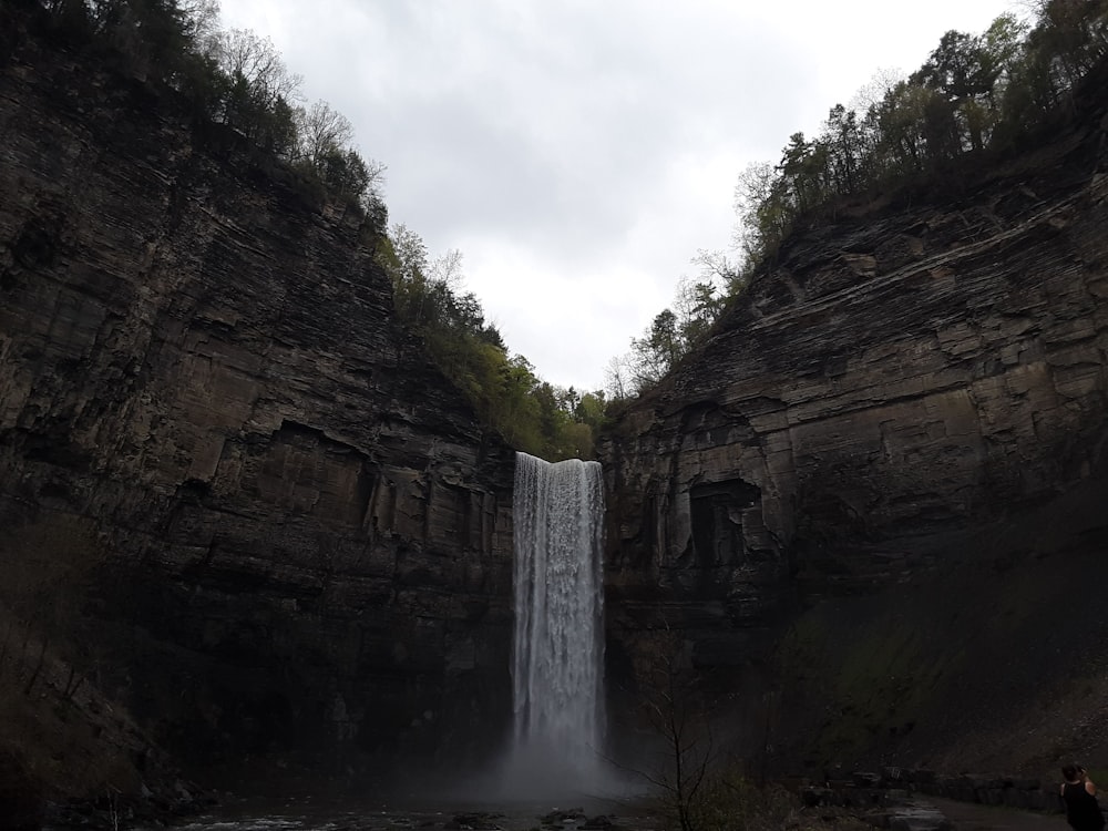 Una persona parada frente a una cascada