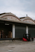 A busy loading dock with forklifts moving heavy machinery.