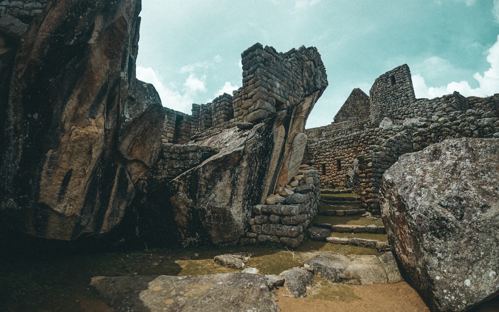 a stone structure surrounded by large rocks under a cloudy sky