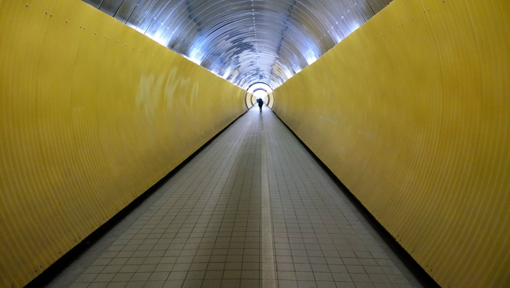 a long yellow tunnel with a person walking through it