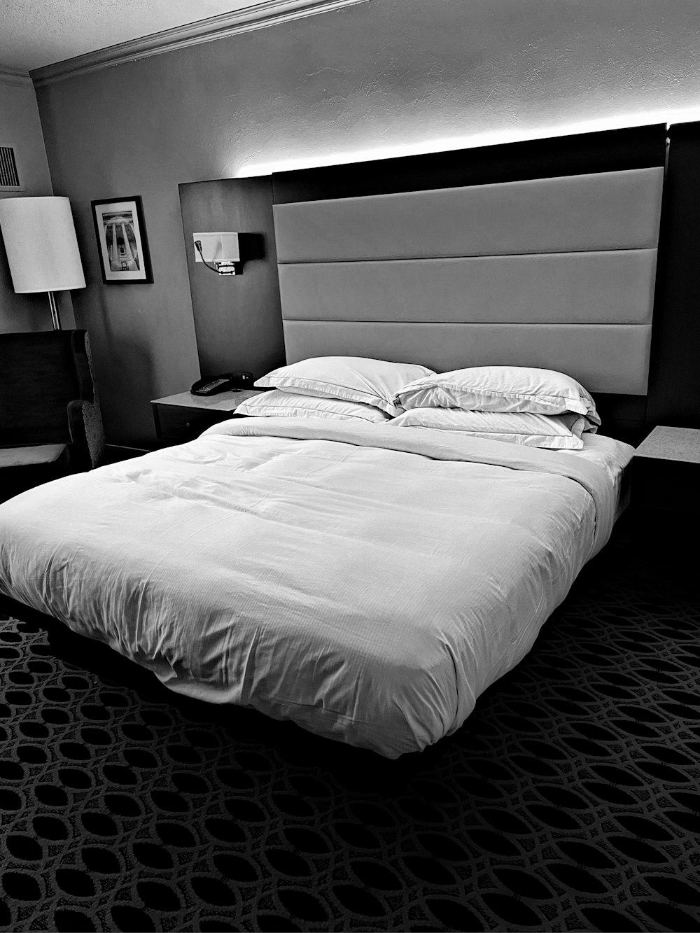 a black and white photo of a bed in a hotel room
