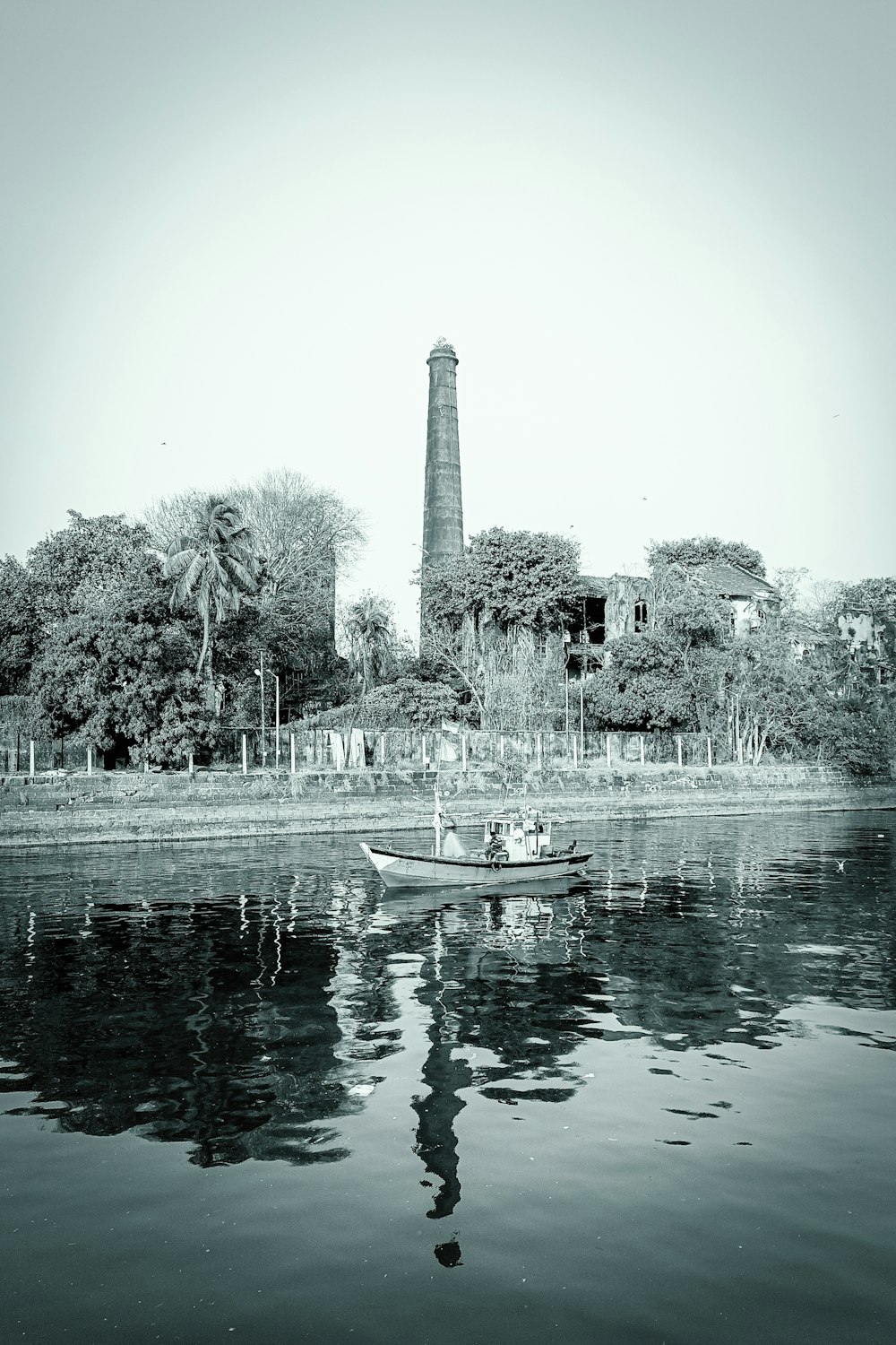 a small boat floating on top of a lake next to a tall tower