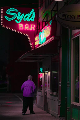 A sleek neon-lit entrance of Bongos nightclub glowing in electric purple and gold against a deep black background.