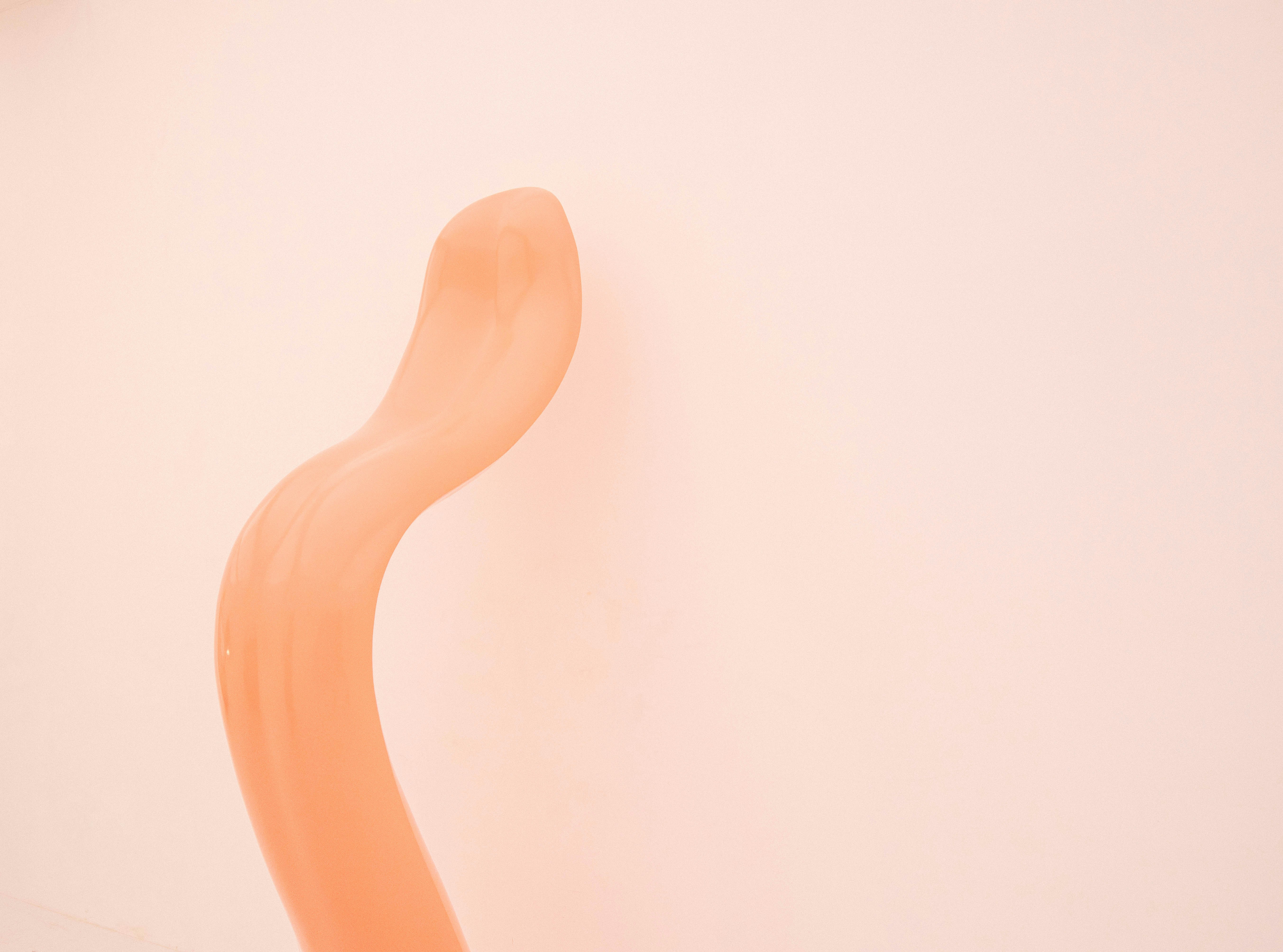 a curved orange object against a white wall