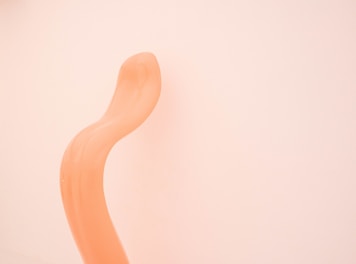 a curved orange object against a white wall
