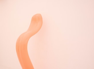 a curved orange object against a white wall