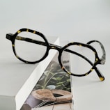 Elegant tortoiseshell round glasses displayed on a soft fabric background.