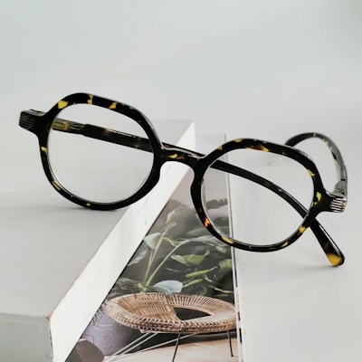 Elegant tortoiseshell round glasses displayed on a soft fabric background.