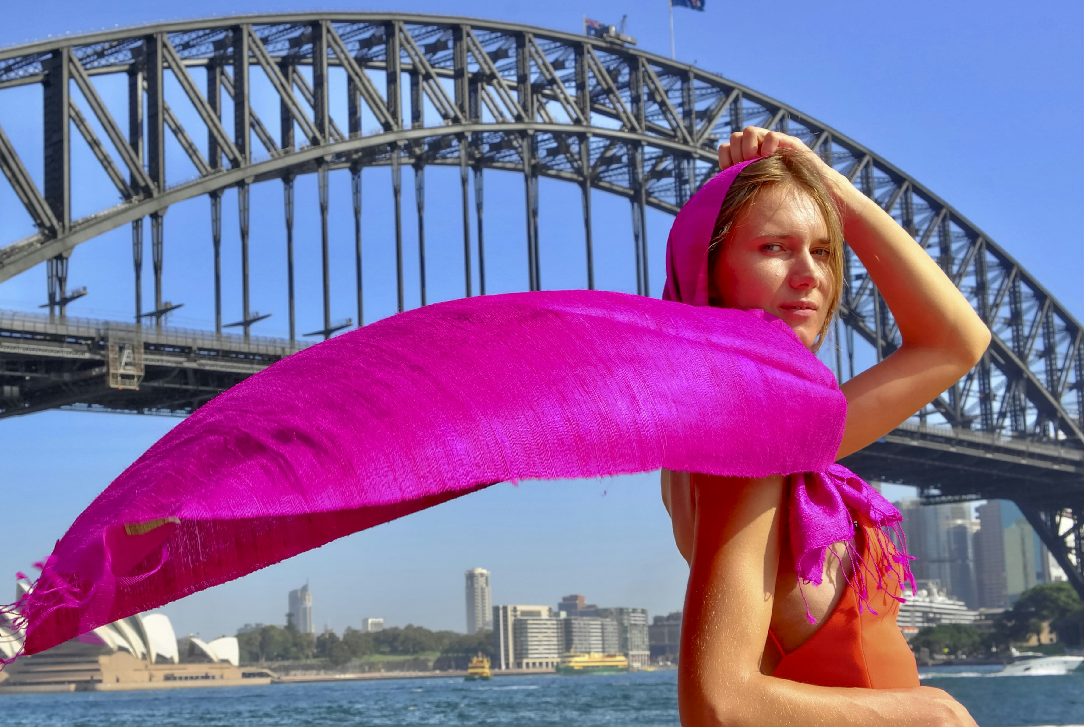 a woman in a bikini holding a pink scarf over her head