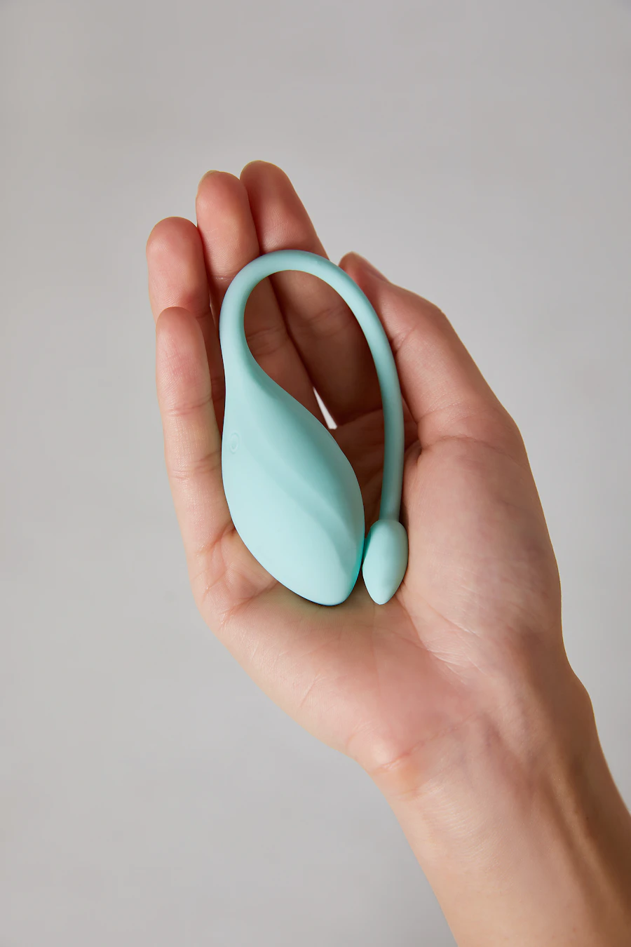 Mint-green pelvic-floor trainer held in an open hand