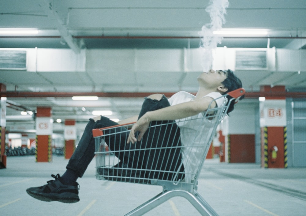 a man laying on top of a shopping cart
