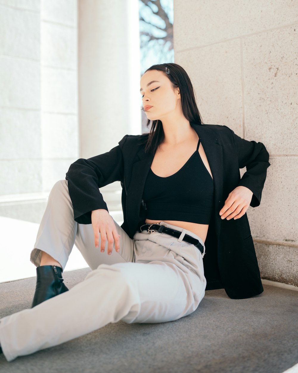 a woman sitting on the ground wearing a black jacket