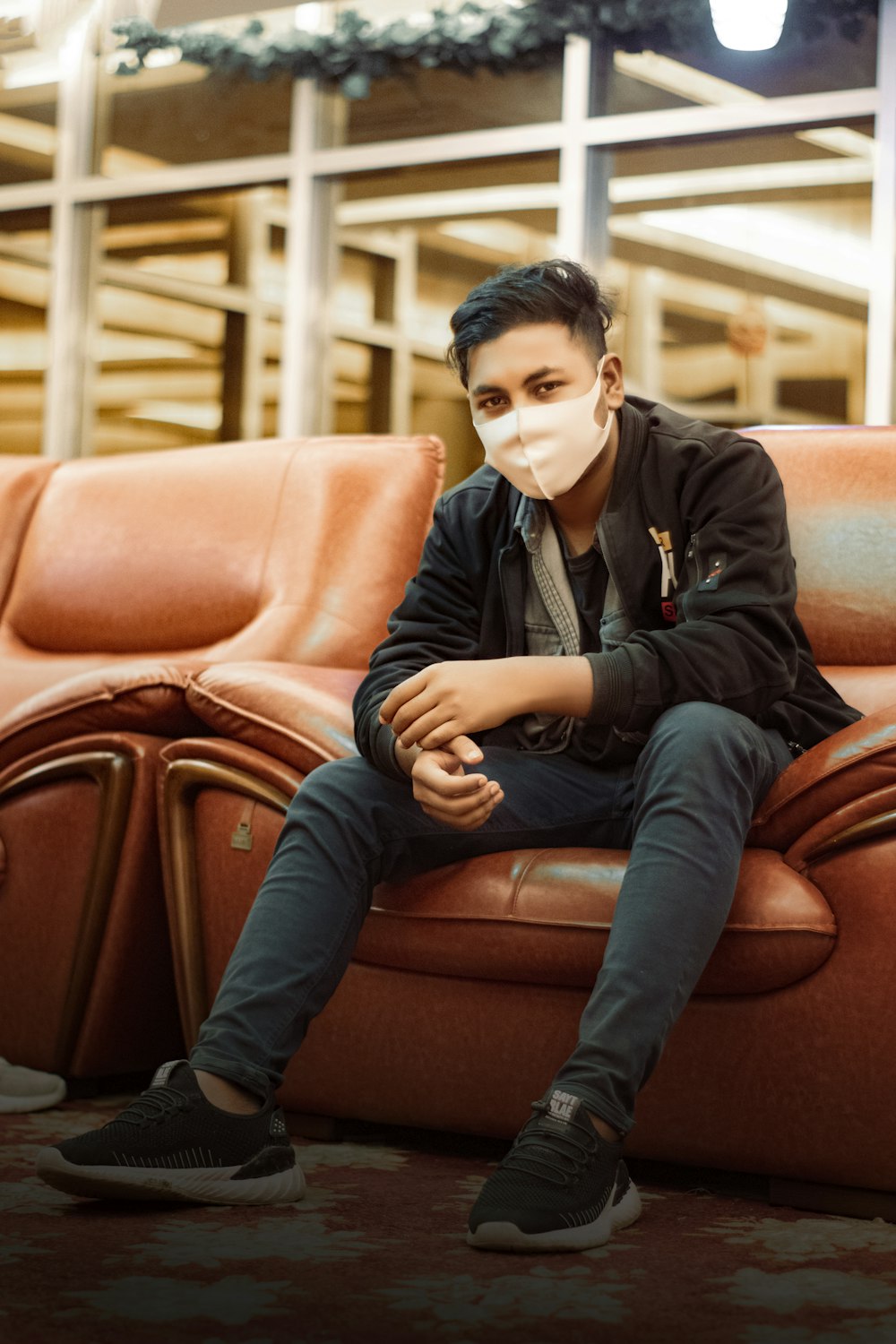 a man sitting on a couch wearing a face mask