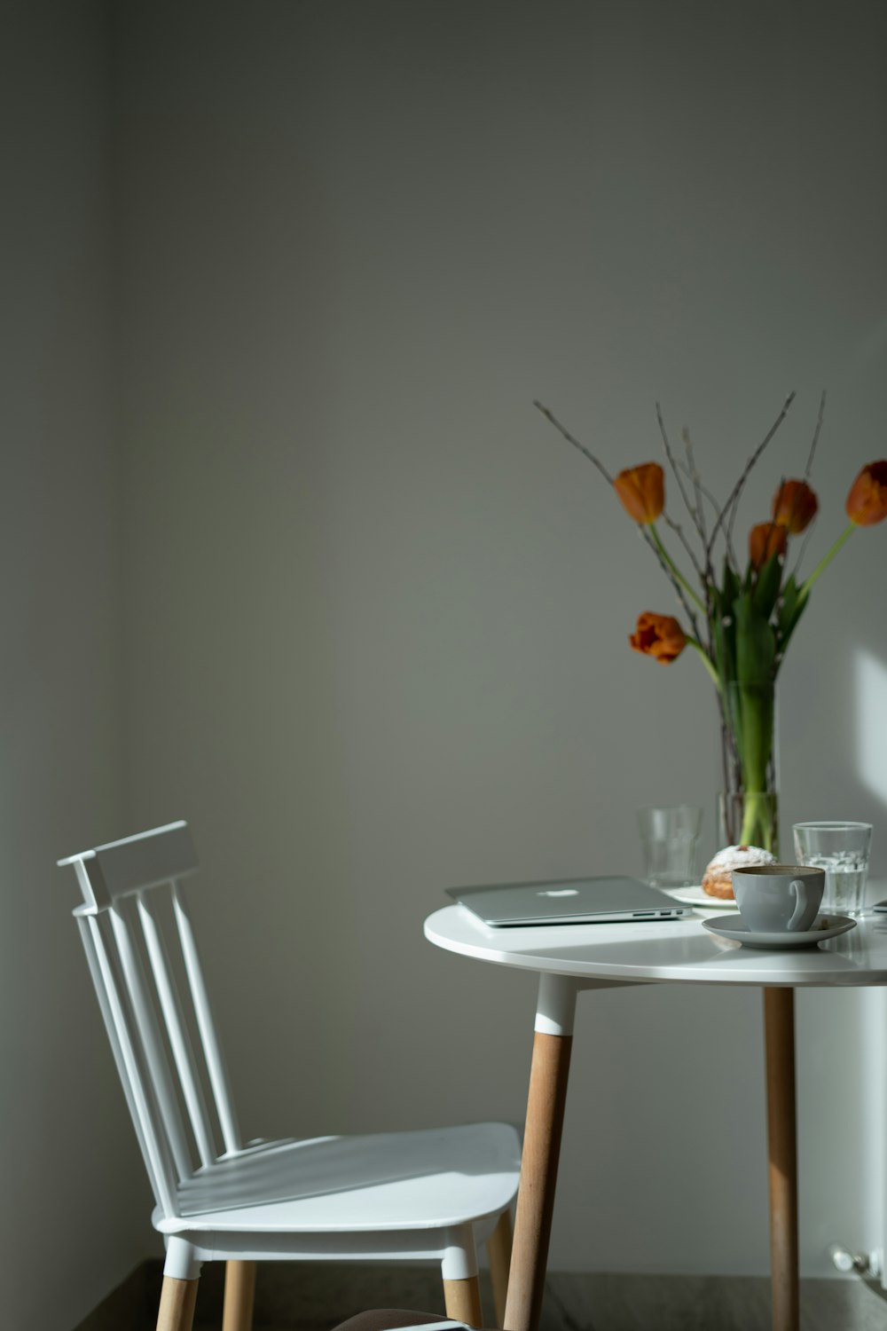 a white table with two chairs and a vase of flowers