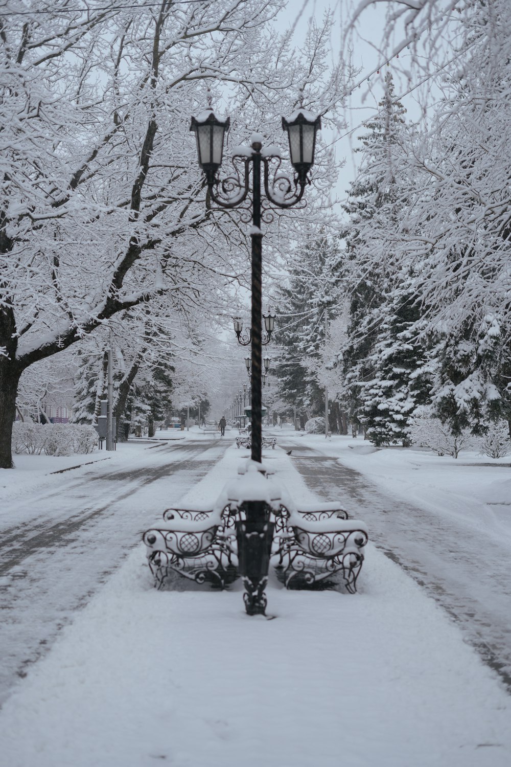 a park bench covered in snow next to a street light