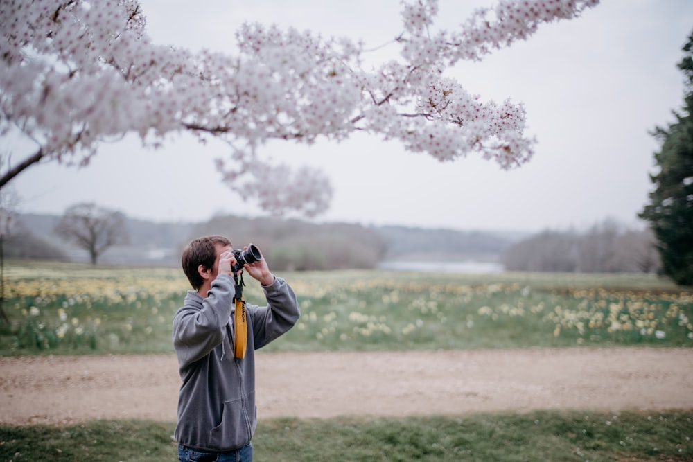 Un homme prenant une photo d’un arbre avec un appareil photo