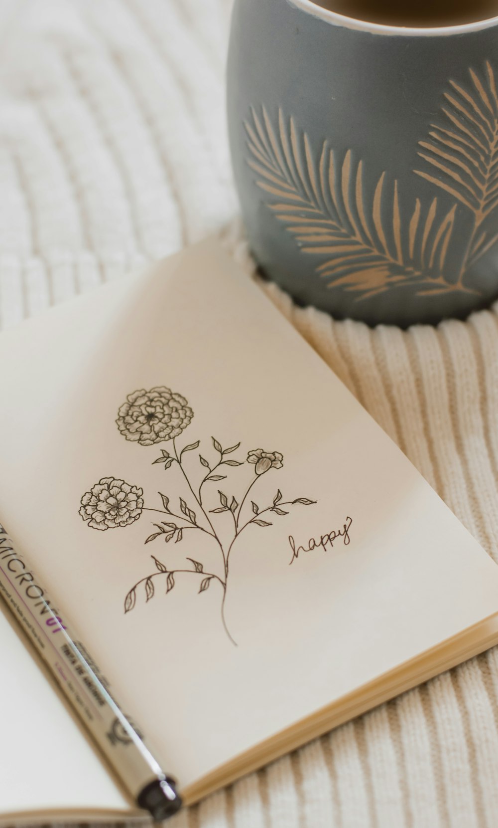 a notebook with a drawing of a flower next to a cup of coffee