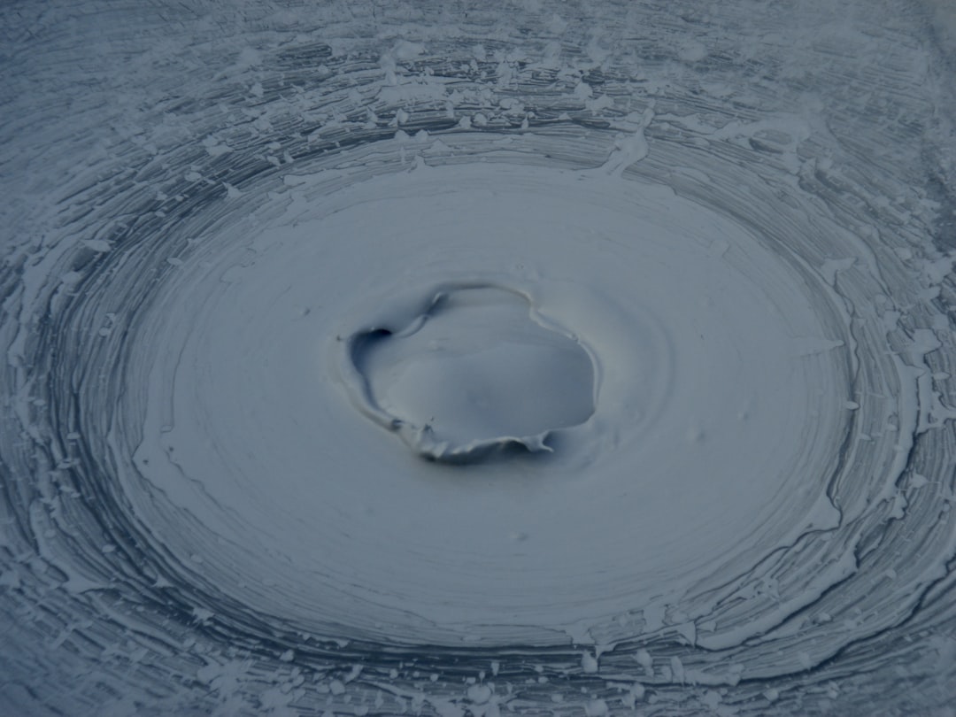 a circular hole in the middle of a snow covered ground, Muddy water in Japanese hot spring