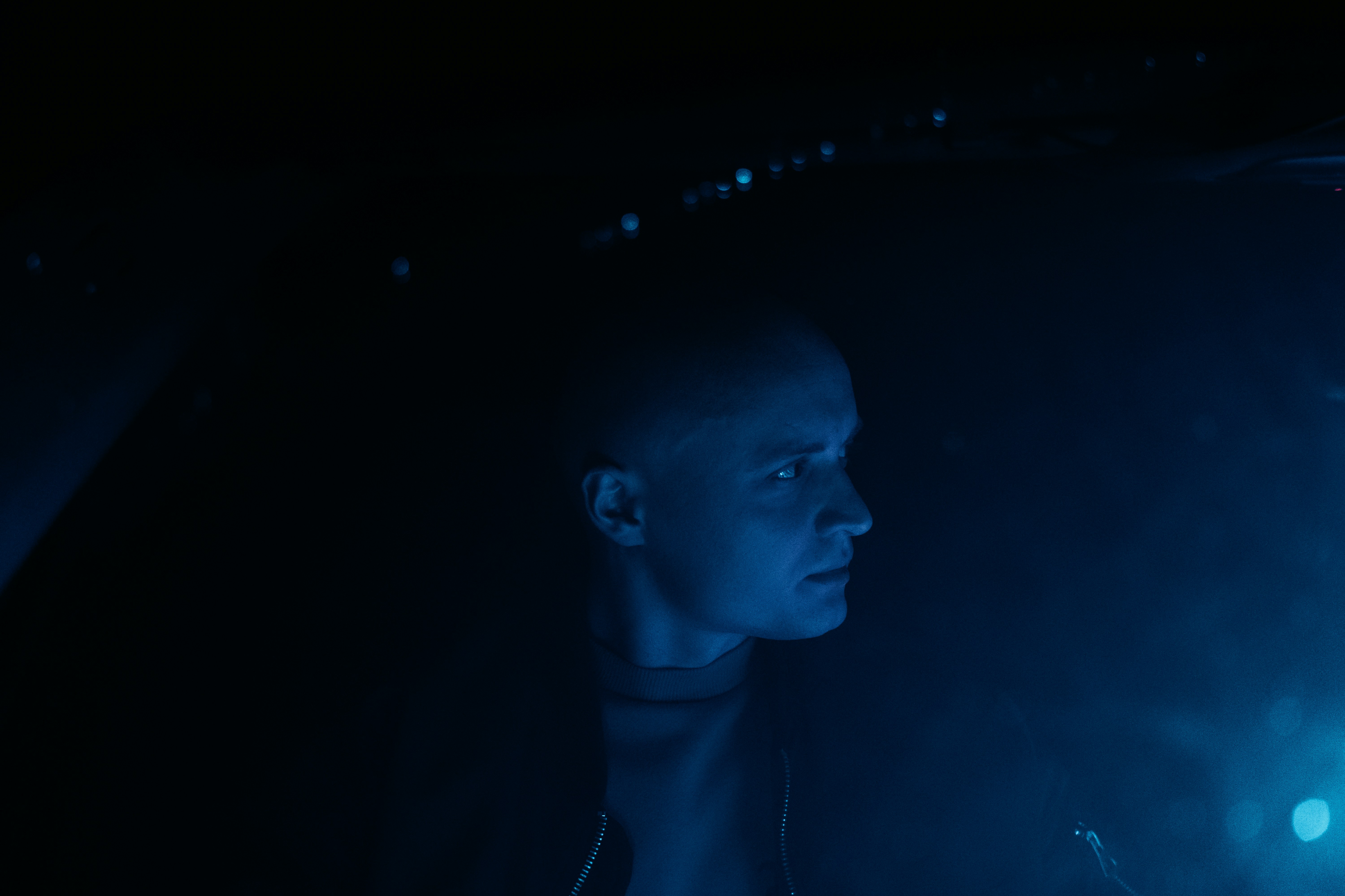 a man standing in the dark with his head turned to the side