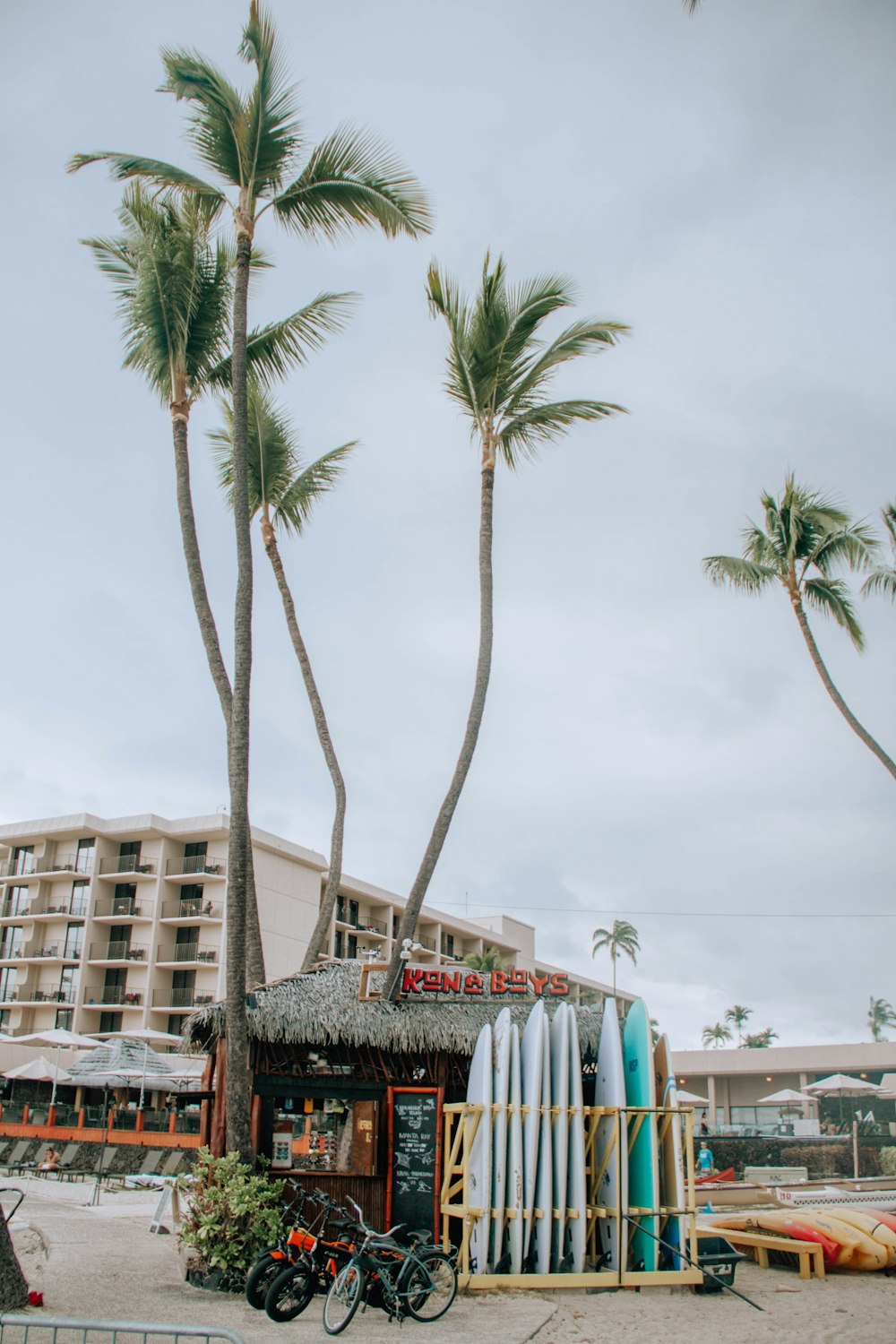 a surfboard stand in front of a hotel with palm trees