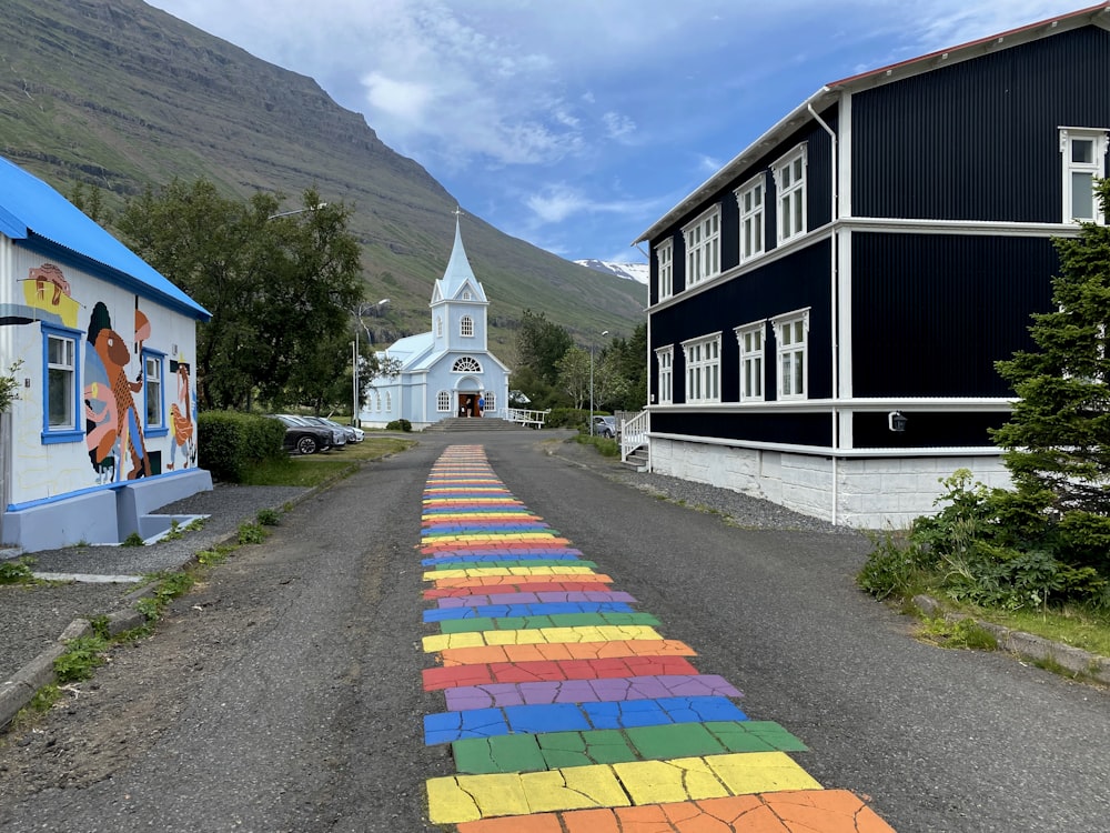 a rainbow painted street with a church in the background