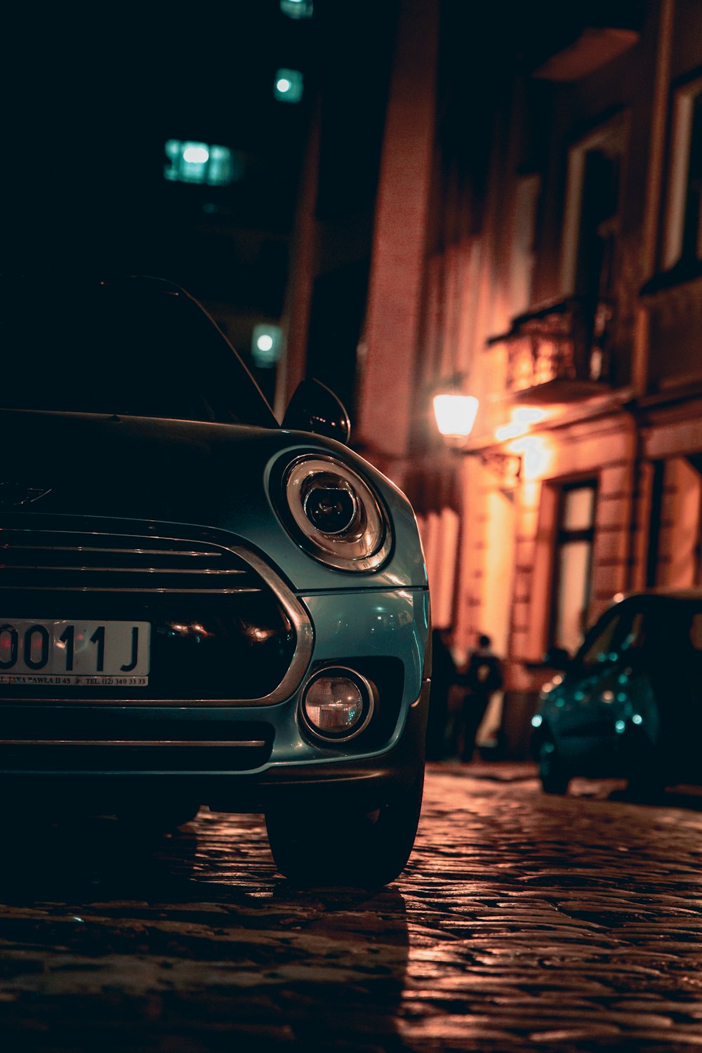 a small car parked on a cobblestone street at night