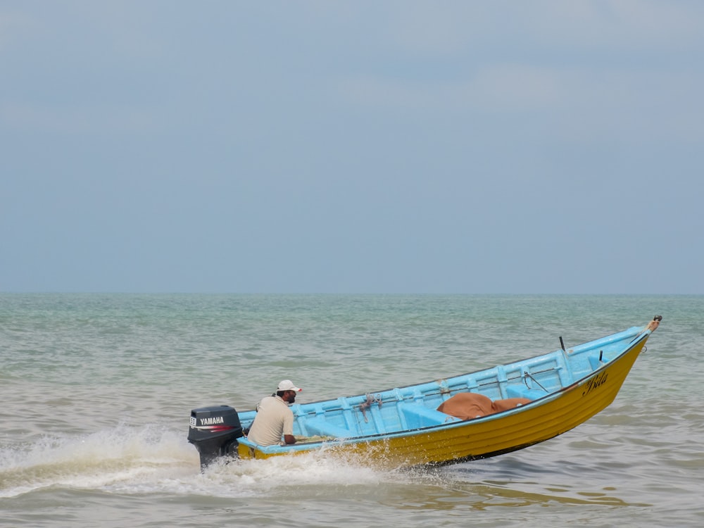 a man in a blue and yellow boat in the water