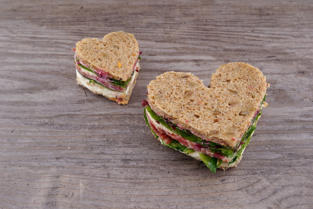 a heart shaped sandwich cut in half on a wooden table