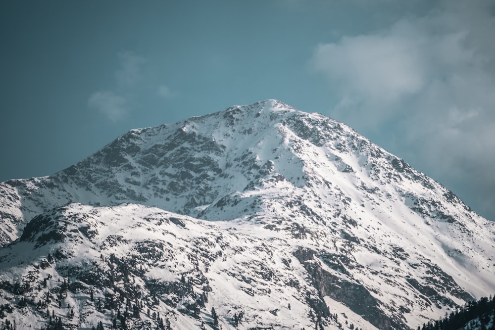 a mountain covered in snow under a cloudy sky